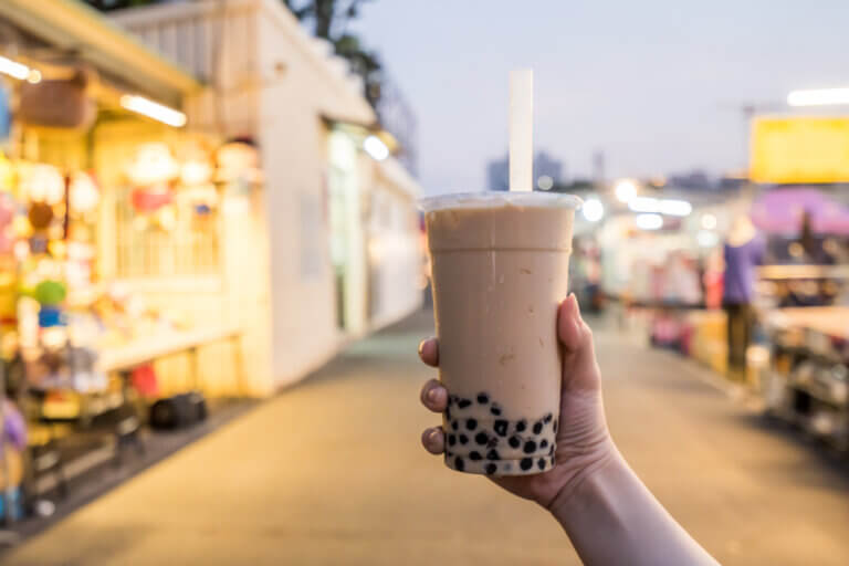 An image of a hand holding a cup of boba tea outdoors