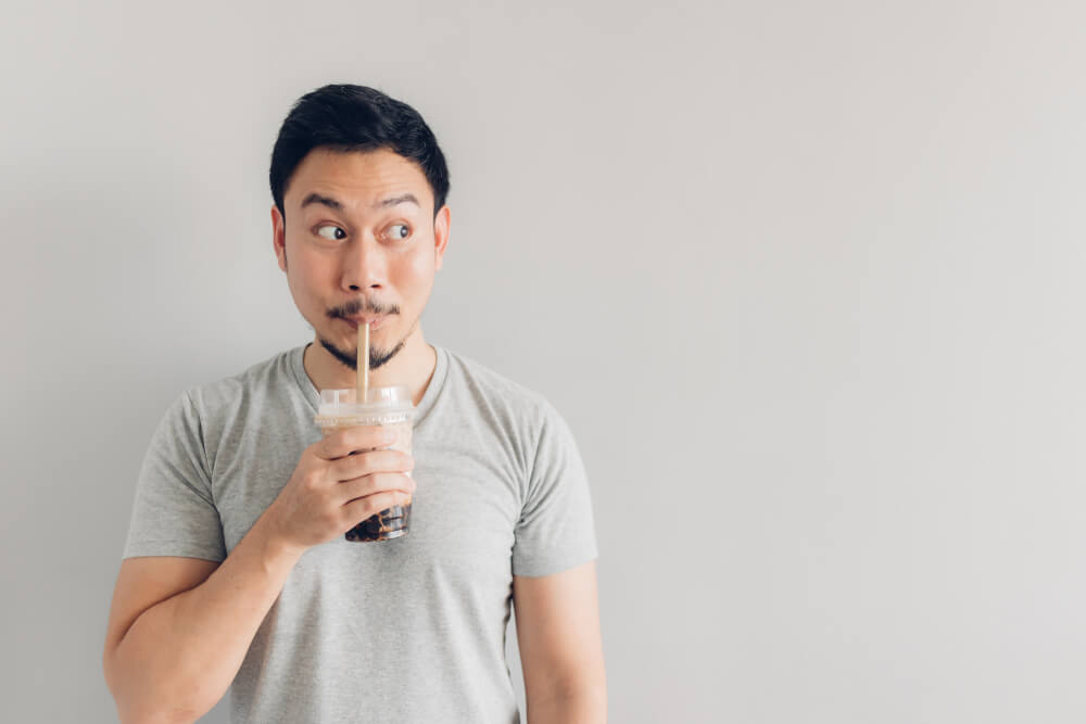 Image of a man drinking a take-out boba drink