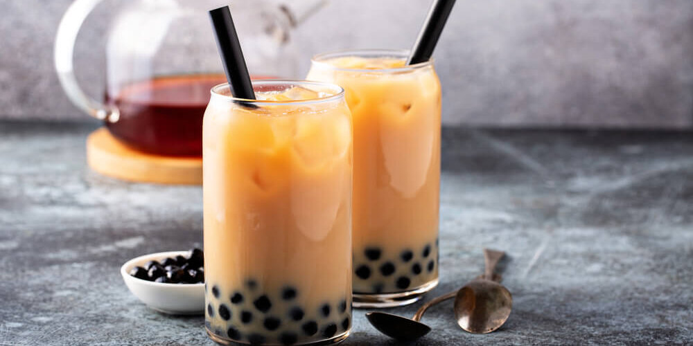 Milk,Bubble,Tea,With,Tapioca,Pearls,And,Honey Image of two boba milk tea drinks in a glass
