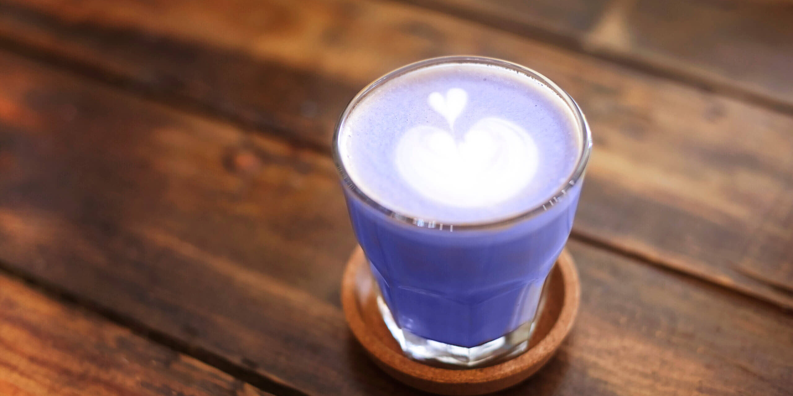 Glass mug with latte on wooden table
